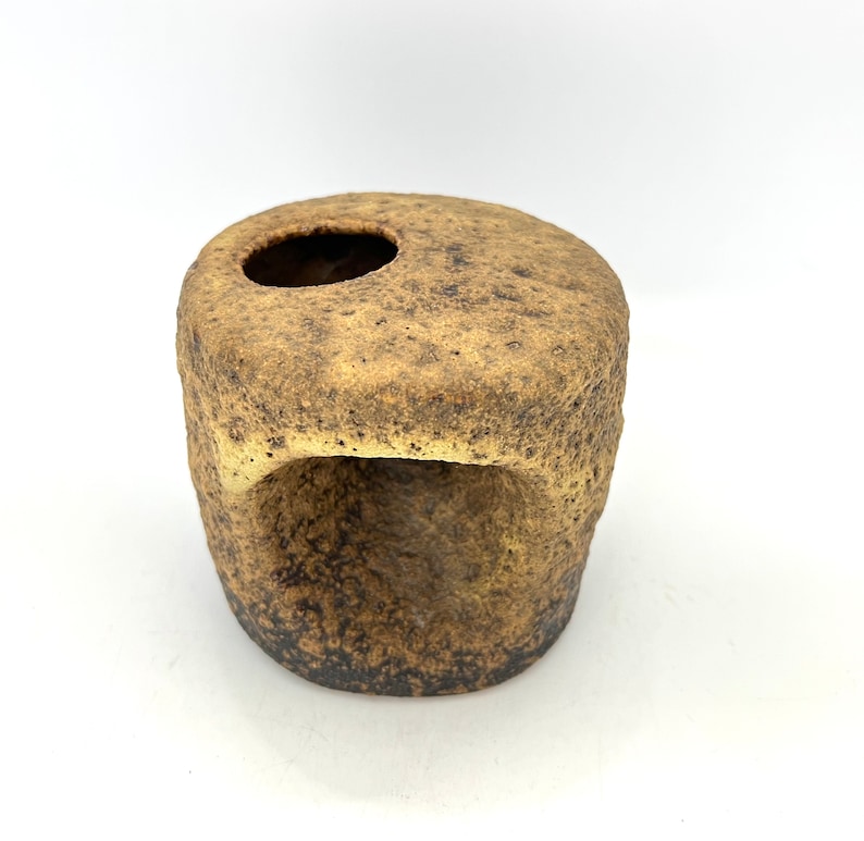 K&ouml;nnte beinhalten: Eine kleine, braune Keramikvase mit einer rauen, strukturierten Oberfl&auml;che. Die Vase hat zwei &Ouml;ffnungen, eine oben und eine an der Seite.