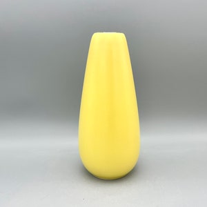 May include: A yellow ceramic vase with a rounded, teardrop shape.