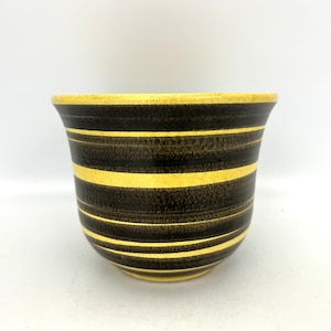 May include: A yellow and black striped ceramic planter. The planter has a wide base and a narrow opening.