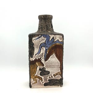 May include: Rectangular ceramic vase with a textured, dark brown neck and base. The body features a cream-coloured background with brown, blue, and yellow horse figures. The vase has a unique, artistic design.