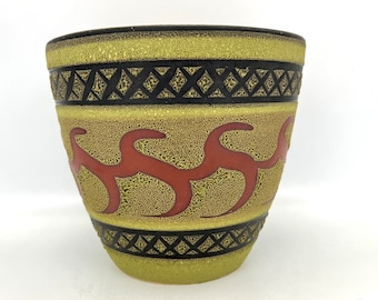May include: A green ceramic planter with a black and white geometric pattern and red wavy lines. The planter has a textured surface.