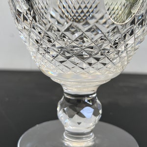 May include: A clear glass goblet with a diamond-shaped pattern on the bowl and stem. The goblet has a round base.