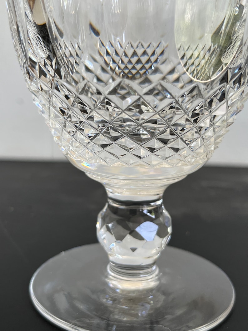 May include: A clear glass goblet with a diamond-shaped pattern on the bowl and stem. The goblet has a round base.