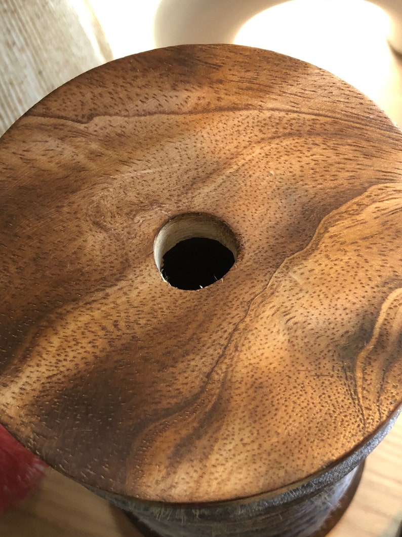May include: A wooden spool with a hole in the centre. The wood has a natural brown colour and a grainy texture.