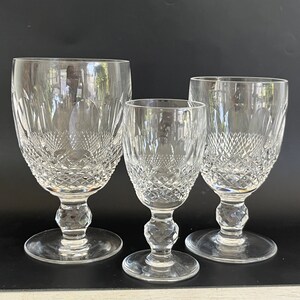 May include: Three clear glass goblets with a cut crystal design. The goblets are of different sizes, with the largest goblet in the back and the smallest goblet in the front.