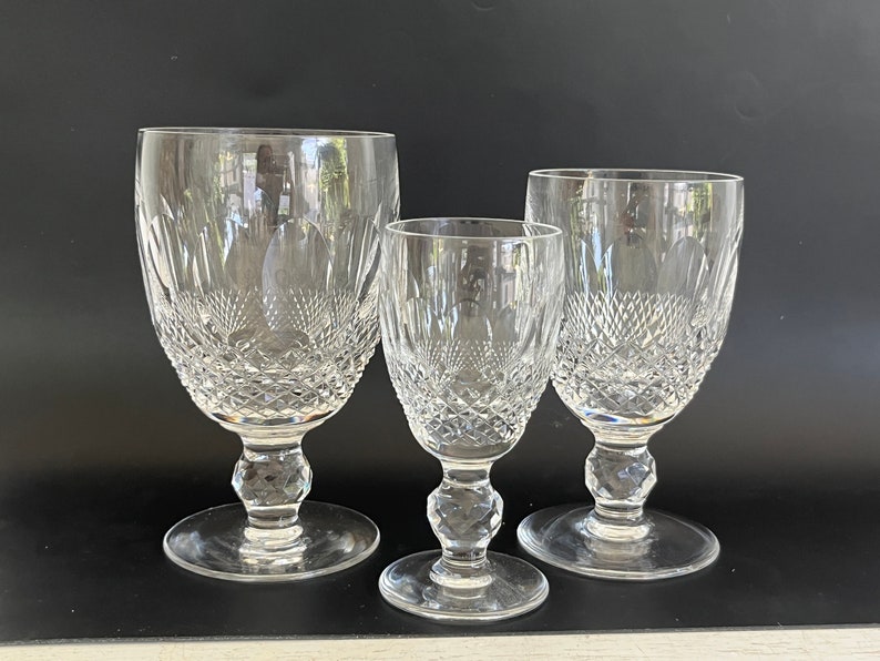 May include: Three clear glass goblets with a cut crystal design. The goblets are of different sizes, with the largest goblet in the back and the smallest goblet in the front.