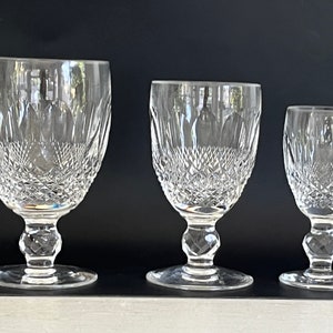 May include: Three clear glass goblets of varying sizes with a cut crystal design. The goblets have a round bowl and a stem with a round base.