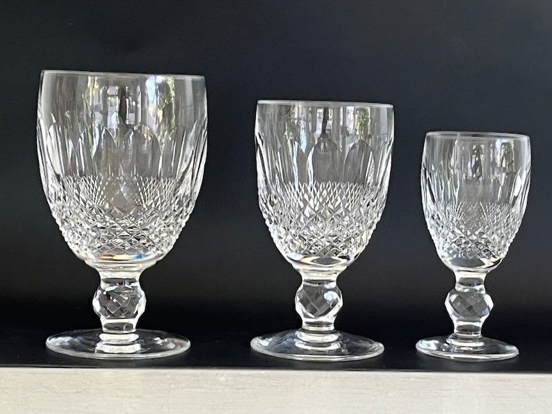 May include: Three clear glass goblets of varying sizes with a cut crystal design. The goblets have a round bowl and a stem with a round base.