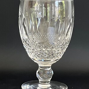 May include: A clear crystal goblet with a cut glass design. The goblet has a wide bowl and a tall stem with a round base.