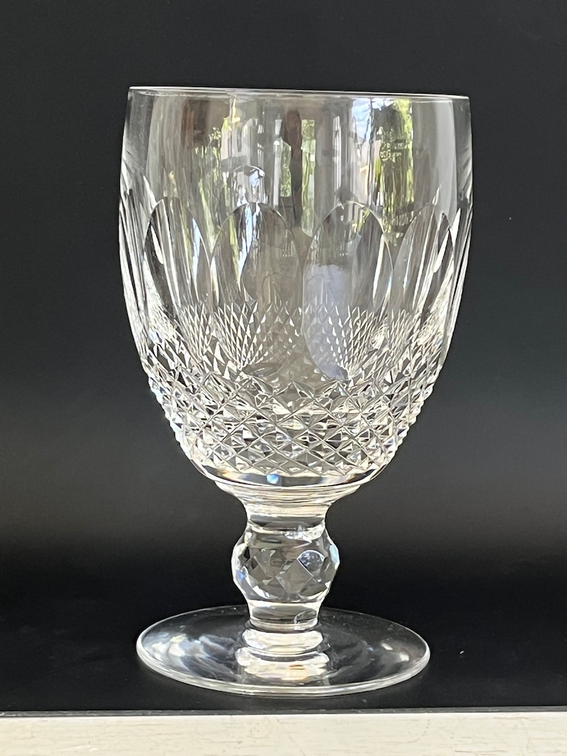 May include: A clear crystal goblet with a cut glass design. The goblet has a wide bowl and a tall stem with a round base.