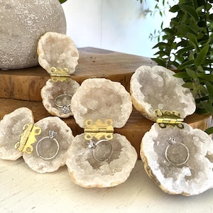 May include: Five white agate geode ring boxes with gold hinges. Each box is open and has a ring inside.