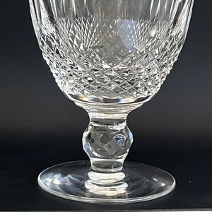 May include: A clear glass goblet with a diamond-shaped pattern. The goblet has a tall, slender stem and a wide, round base.