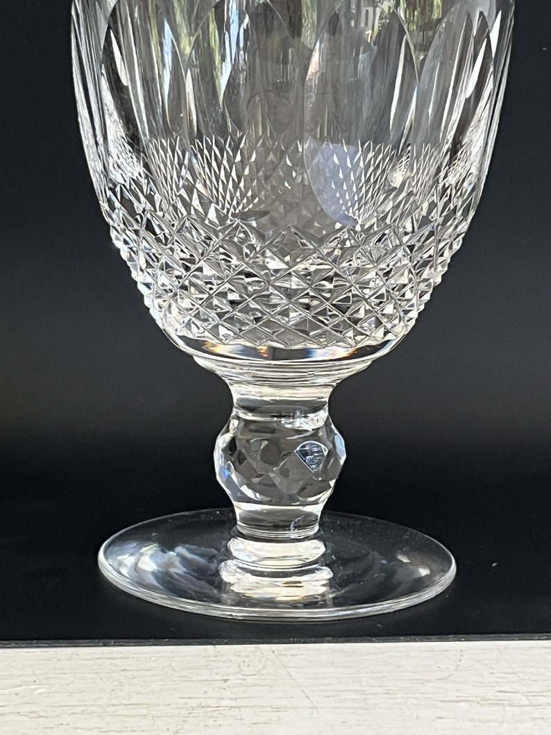 May include: A clear glass goblet with a diamond-shaped pattern. The goblet has a tall, slender stem and a wide, round base.