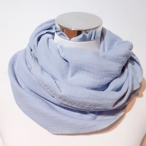 Könnte beinhalten: Ein hellblauer Schal aus Baumwolle mit schlichtem Design. Der Schal ist gefaltet und auf einer Puppe ausgestellt.