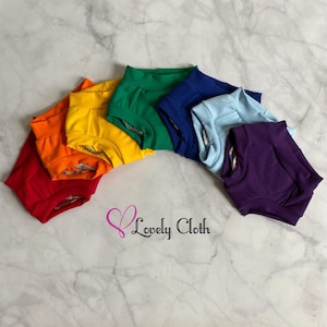May include: A rainbow assortment of seven pairs of colorful baby bloomers. The bloomers are made of soft, stretchy fabric and are perfect for everyday wear.  The colors are red, orange, yellow, green, blue, light blue, and purple.
