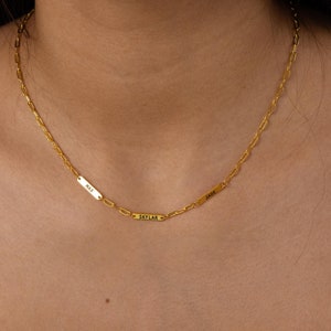Könnte beinhalten: Eine goldene Kettenkette mit drei kleinen rechteckigen Namensschildern. Die Namensschilder tragen die Namen "JADE", "SKYLAR" und "MIA".