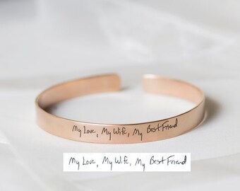 May include: A rose gold cuff bracelet with the handwritten inscription "My Love, My Wife, My Best Friend".