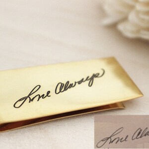 May include: A gold-colored money clip with the inscription "Love Always" engraved in black.