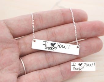 May include: Silver necklace with a rectangular bar pendant engraved with the handwritten message "I love you!! Brooke" with a heart drawn next to each word.