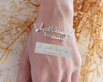 May include: A silver bracelet with the words "I will love you forever" written in cursive. The bracelet is on a person's wrist and there is a note with the same message on the person's hand.