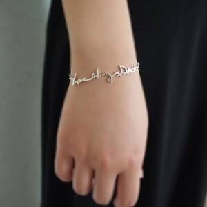 May include: Silver bracelet with the words "Love always Dad" written in cursive.