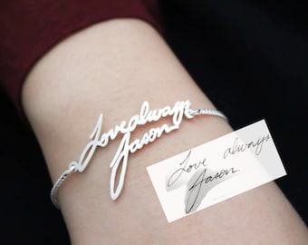 May include: A silver bracelet with the words "Love always Jason" written in cursive. The bracelet is on a person's wrist. A handwritten note with the same words is shown in the background.