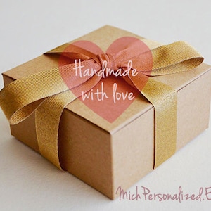 May include: A brown cardboard gift box tied with a gold ribbon and a pink heart sticker that says "Handmade with love".