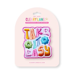 May include: A colorful embroidered iron-on patch with the text "Take it easy" in a playful font. The patch features flowers and a pink outline.