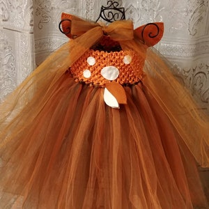 A brown tulle tutu dress with a white deer spots on the back of the bodice and a brown felt deer tail. The dress has brown tulle straps that can tie at the neck or back of the dress.