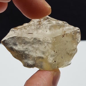 May include: A clear, translucent, irregularly shaped piece of quartz with a rough, textured surface. The quartz has a light brown hue and appears to have some inclusions.