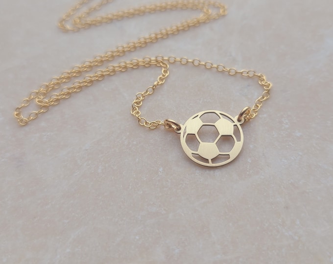May include: A gold chain necklace with a delicate, cut-out soccer ball pendant.