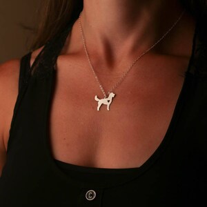 Model in black shirt is wearing silver Goldendoodle dog cutout charm necklace.  Heart is cutout on right side.  Charm is on sterling silver delicate cable chain.