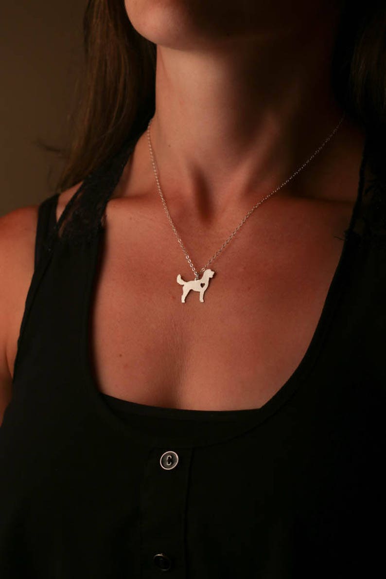 Model in black shirt is wearing silver Goldendoodle dog cutout charm necklace.  Heart is cutout on right side.  Charm is on sterling silver delicate cable chain.