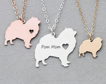 May include: Three silver necklaces with a Pomeranian silhouette pendant. The middle pendant has the text "Pom Mom" engraved on it.