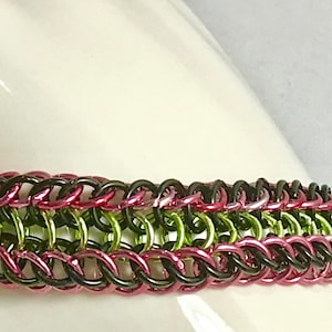 Chainmaille bracelet in black, pink and green jump rings .