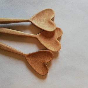 May include: Three wooden spoons with heart-shaped bowls. The spoons are stacked on top of each other, with the heart-shaped bowls facing the viewer.