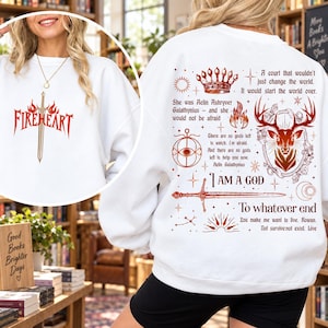 May include: A white long-sleeve sweatshirt featuring a red graphic of a sword and the word FIREHEART on the front. The back displays a red print of a crown, a deer, a sword, and text including A court that wouldn't just change the world.