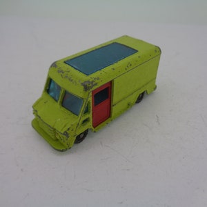 May include: A lime green toy van with a blue roof and a red door. The van has a worn, vintage look.