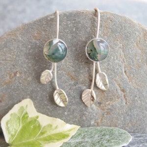 May include: A pair of silver dangle earrings with green agate stones and silver leaf accents.