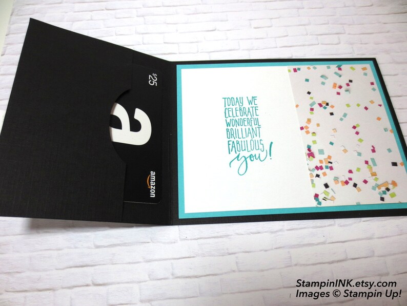 May include: A black gift card holder with an Amazon gift card visible. The card holder is open, revealing a white interior with the text "Today we celebrate wonderful brilliant fabulous you!" and a confetti pattern.