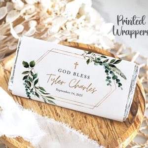 May include: White chocolate bar wrapper with a gold geometric frame and green foliage. The text reads "God Bless Tyler Charles September 14, 2025".