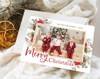 May include: A Christmas card with a family photo inside a gold border, surrounded by watercolor floral and greenery. The words "Merry Christmas" are in red script. The family name and year are at the top. The card is on a white envelope.