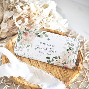 May include: A white chocolate bar wrapper with a floral design and the text "God Bless Jacinda Rose May 29, 2024".