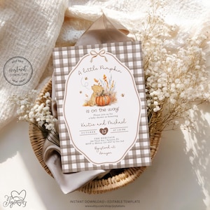 May include: A rectangular baby shower invitation card featuring a brown and white gingham border and a central illustration of a bear with a pumpkin. The text reads A little Pumpkin is on the way, honouring Kristie and Michael on October 12.