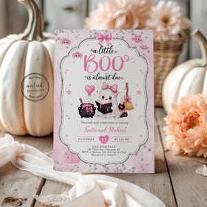May include: A rectangular baby shower invitation card featuring a pink and white theme with a ghost illustration, a cauldron, a broom, and the text 'a little BOO is almost due'. The design includes pink bows, stars, and bats, with placeholders for names, date, time, and location details.