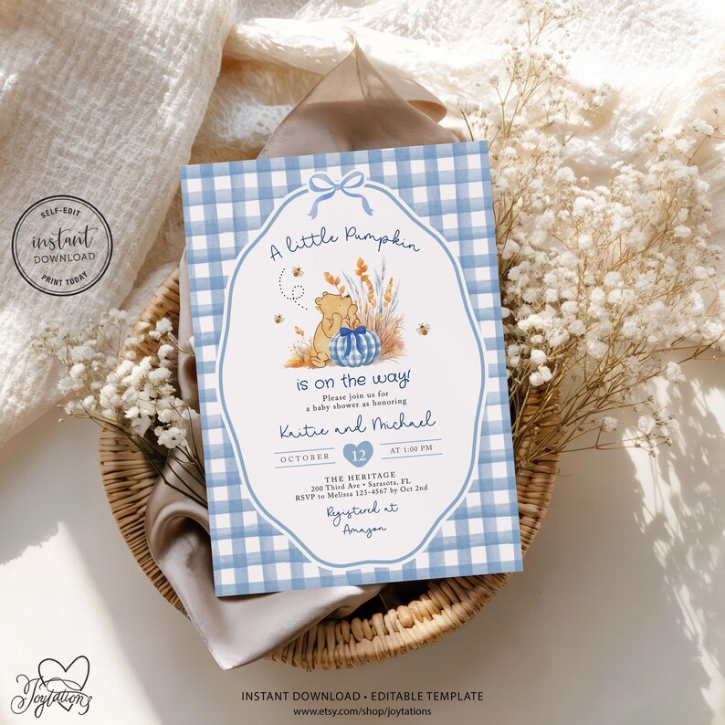 May include: A rectangular baby shower invitation card featuring a light blue and white gingham border. The center displays a cartoon bear, a blue gingham pumpkin, and wheat stalks. Text reads: A little Pumpkin is on the way! Kaitie and Michael.