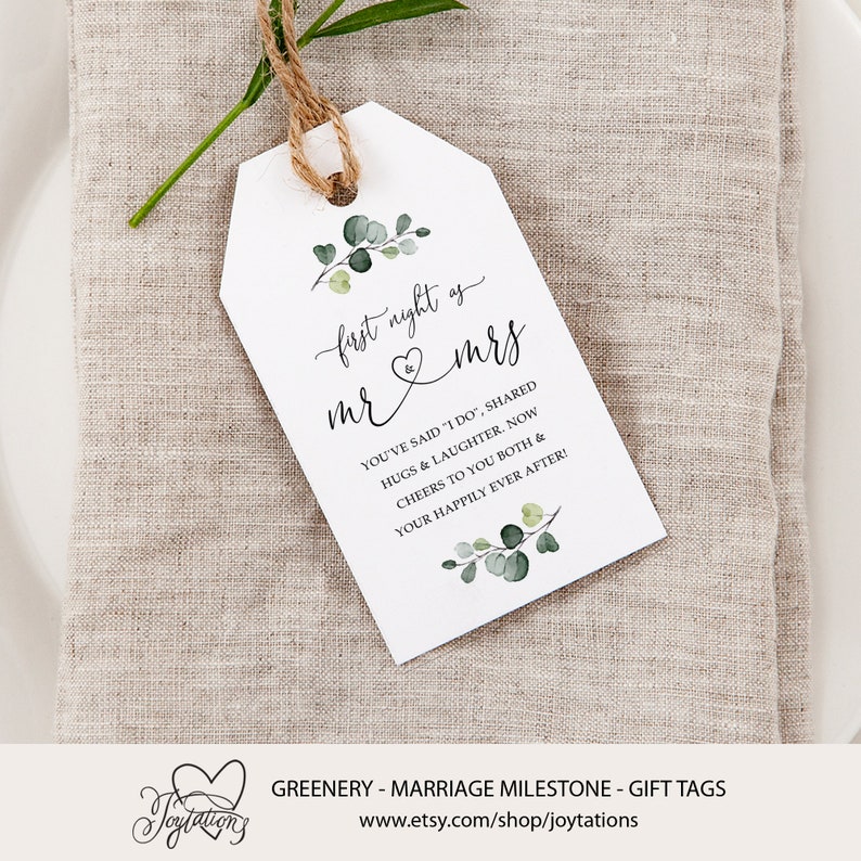 May include: White gift tag with green foliage and the text "first night as mr & mrs" and "You've said "I do", shared hugs & laughter. Now cheers to you both & your happily ever after!"