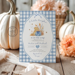May include: A rectangular baby shower invitation card featuring a light blue and white gingham pattern border. The center displays a cartoon bear, a blue gingham pumpkin, wheat stalks, and bees. Text includes A little Pumpkin is on the way.