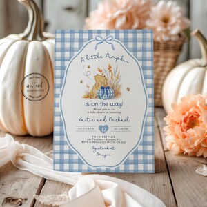 May include: A rectangular baby shower invitation card featuring a light blue and white gingham pattern border. The center displays a cartoon bear, a blue gingham pumpkin, wheat stalks, and bees. Text includes A little Pumpkin is on the way.