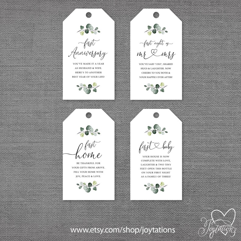 May include: Four white gift tags with green eucalyptus leaves and black calligraphy. The tags read "first anniversary", "first night as mr & mrs", "first home", and "first baby".